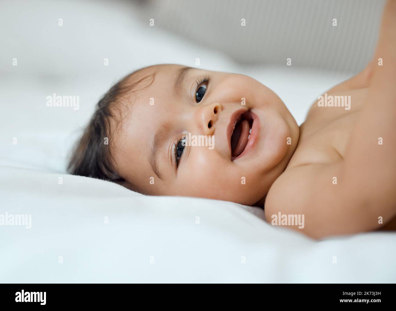 Le sue risate sono solo le più belle. Ritratto di una adorabile bambina sdraiata su un letto a casa. Foto Stock
