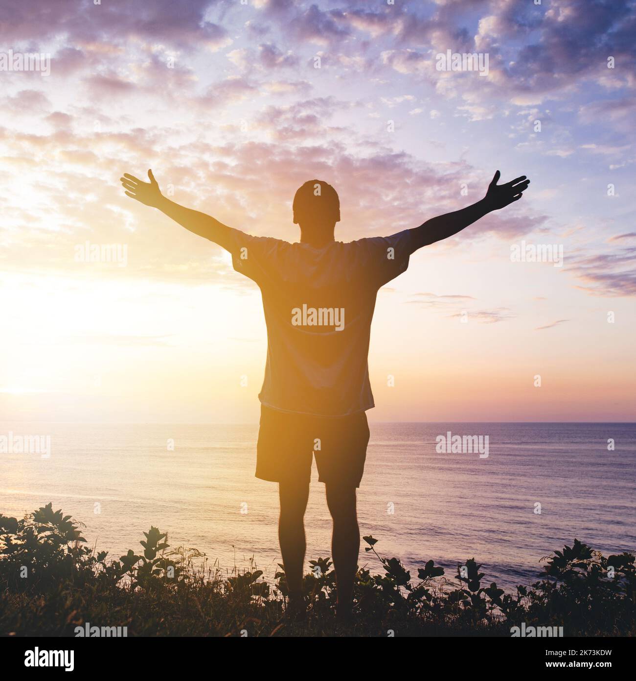 Uomo con le braccia distese per celebrare in un bellissimo tramonto ispirante Foto Stock