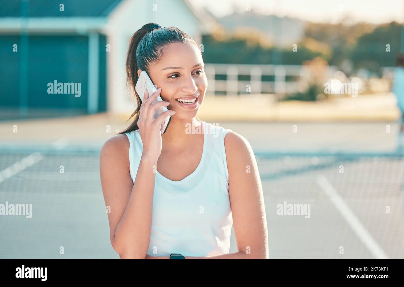 Fantasia una partita di tennis più tardi. una giovane donna attraente in piedi da sola e utilizzando il suo cellulare dopo la pratica del tennis. Foto Stock