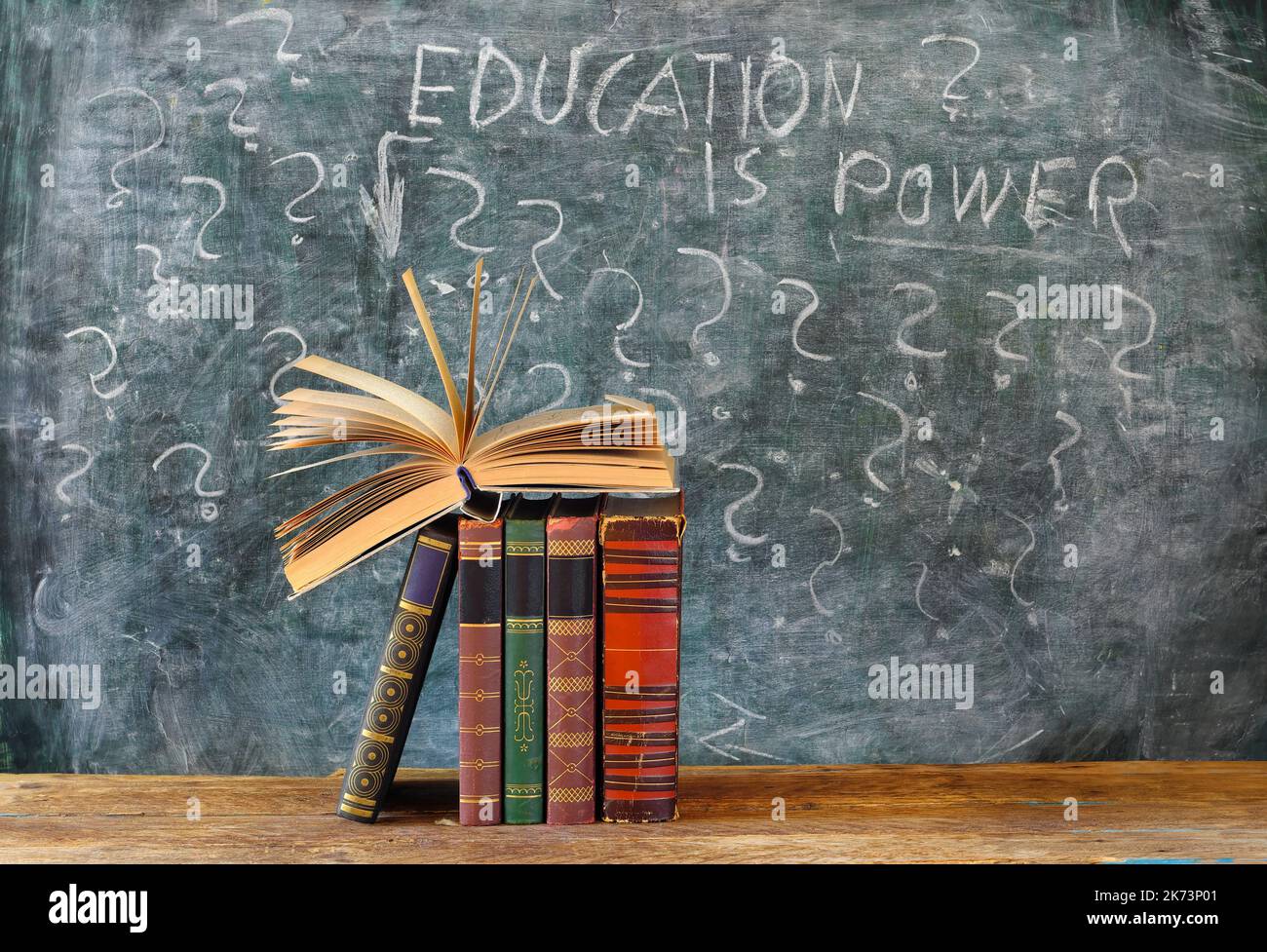 Libro aperto e fila di libri hardback con l'istruzione è slogan di potere su blackboard.Education, conoscenza, concetto di letteratura. Foto Stock