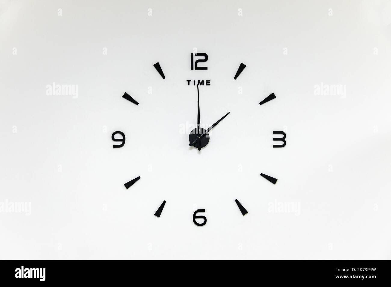 numeri neri minimalisti e frecce di un orologio da parete su sfondo bianco Foto Stock