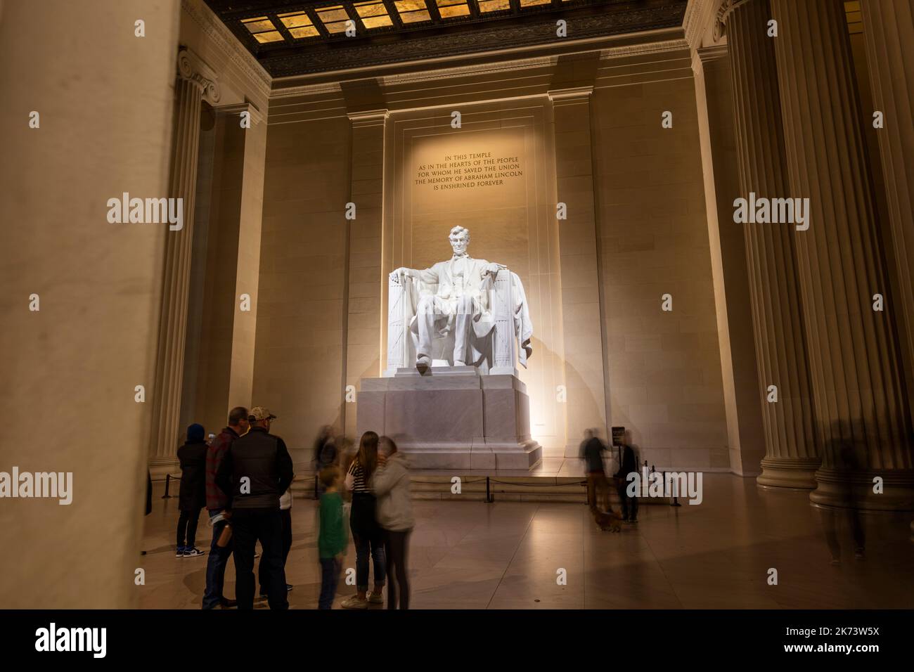 I turisti visitano il Lincoln Memorial a Washington, D.C. di notte in una notte d'inverno. Una lunga esposizione mostra persone sfocate sotto l'imponente statua Foto Stock