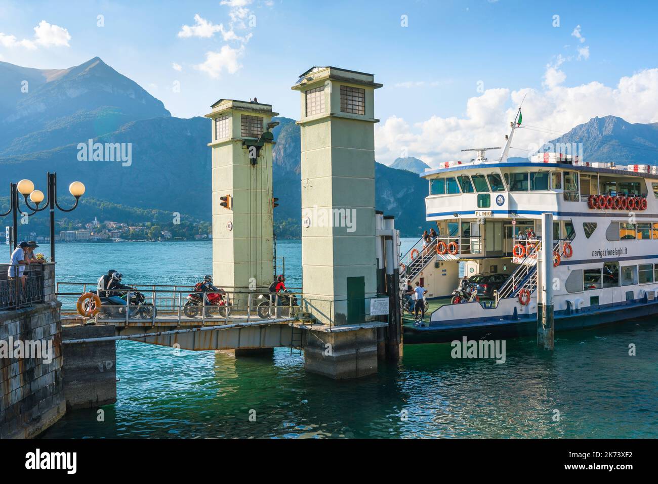 Traghetto Lago di Como moto, vista in estate dei motociclisti a bordo di un traghetto attraccato al molo nella pittoresca città di Bellagio, Italia Foto Stock