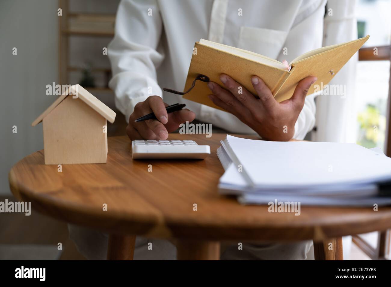 Mano del contabile di affari che calcola gli interessi, le tasse ed i profitti per investire nell'acquisto del bene immobile e della sede Foto Stock