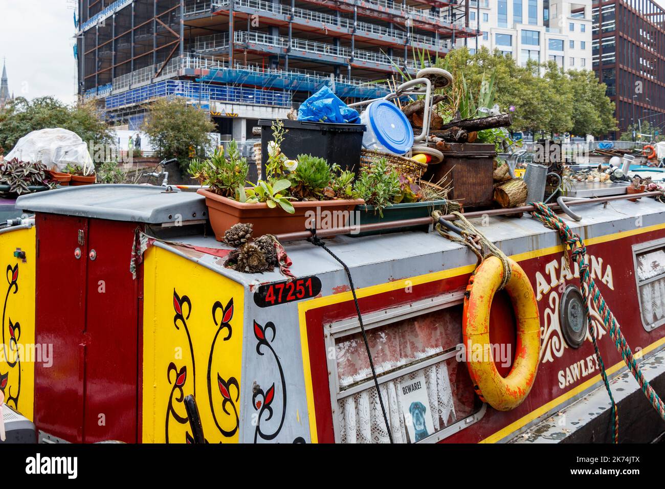 Barche a remi dai colori vivaci sul Regents Canal, lavori di costruzione sulla sponda opposta, King's Cross, Londra, Regno Unito Foto Stock
