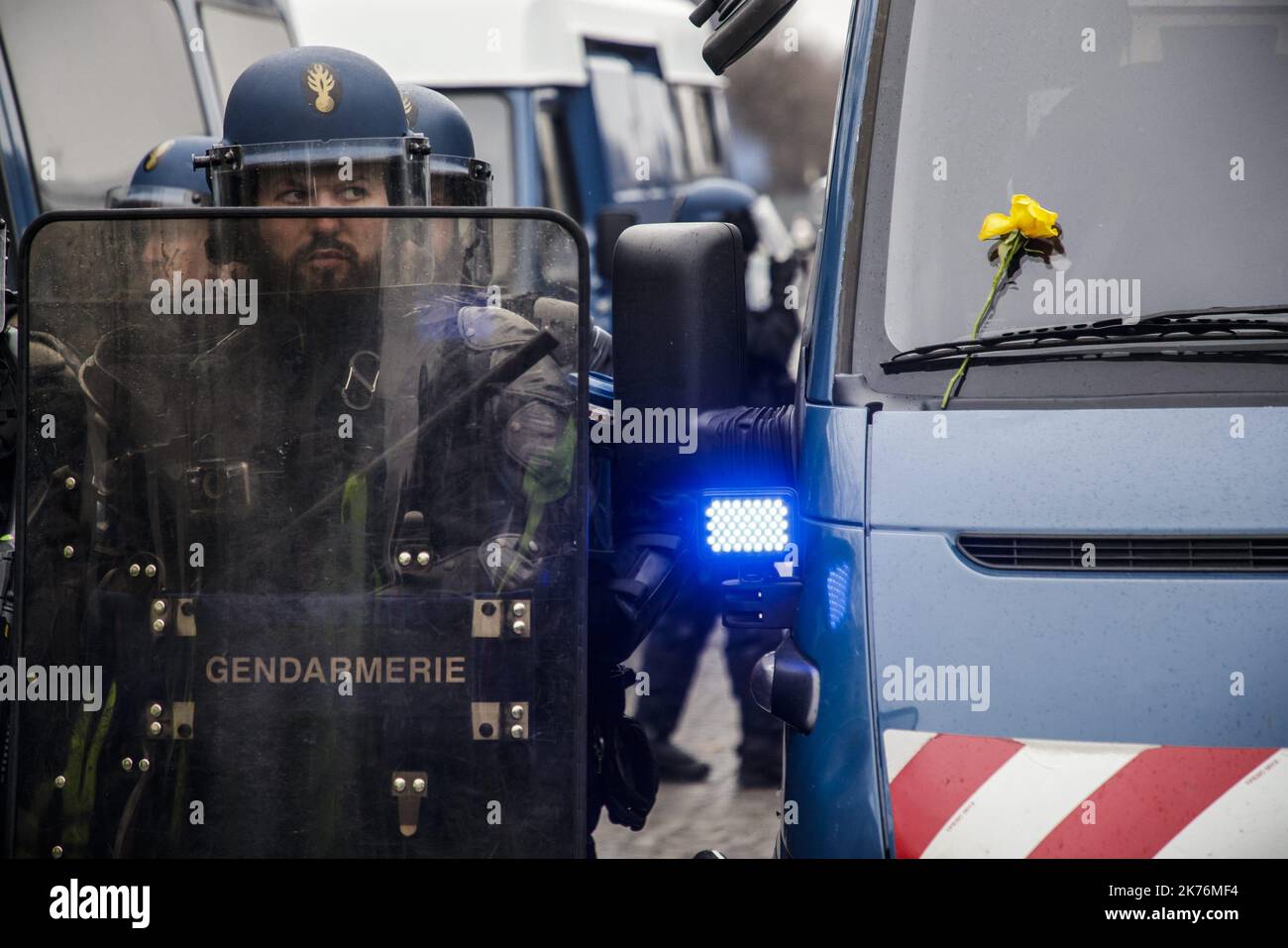 ©Christophe Petit Tesson/MAXPPP - 15/12/2018 ; PARIS ; FRANCIA - une fleur jaune pose par un manifestant sur le prezzo-brise d'un camion de Gendarmerie alors que les Forces de l'Ordre bloque le Passage sur les champs Elysees lors de l'Acte V du mouvement de protestement contre l'augmentation des taxes sur le carburant. Un ufficiale di polizia si trova di fronte a un uomo che indossa un giubbotto giallo mentre tiene fiori gialli durante una manifestazione a Parigi, in Francia, il 15 dicembre 2018. I cosiddetti gilet jaunes (giubbotti gialli) sono un movimento di protesta, che secondo quanto riferito non ha alcuna affiliazione politica, che continua le proteste Foto Stock