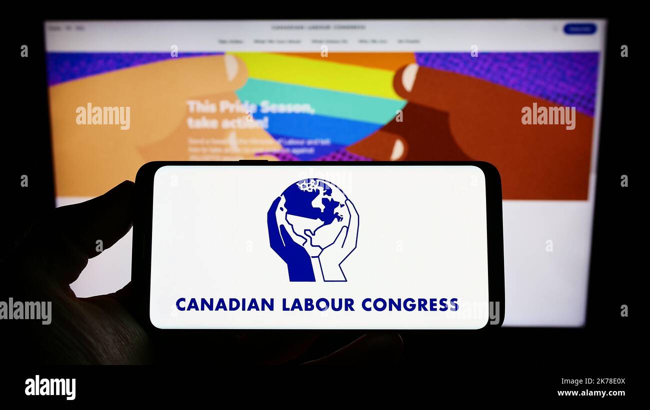 Persona che tiene uno smartphone con il logo del centro sindacale Canadian Labour Congress (CLC) sullo schermo di fronte al sito Web. Messa a fuoco sul display del telefono. Foto Stock
