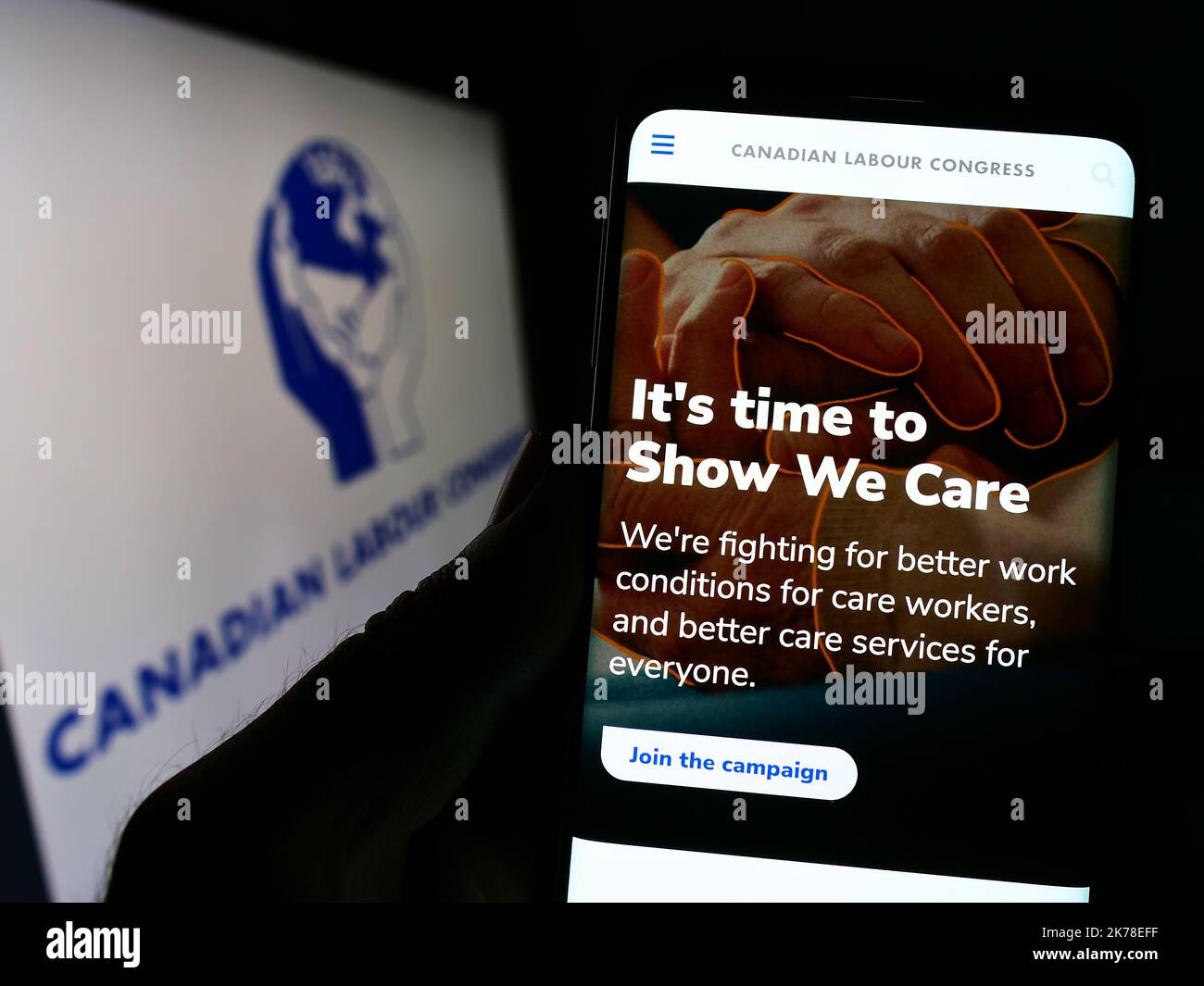 Persona che tiene uno smartphone con il sito Web del centro sindacale Canadian Labour Congress (CLC) sullo schermo con il logo. Messa a fuoco al centro del display del telefono. Foto Stock