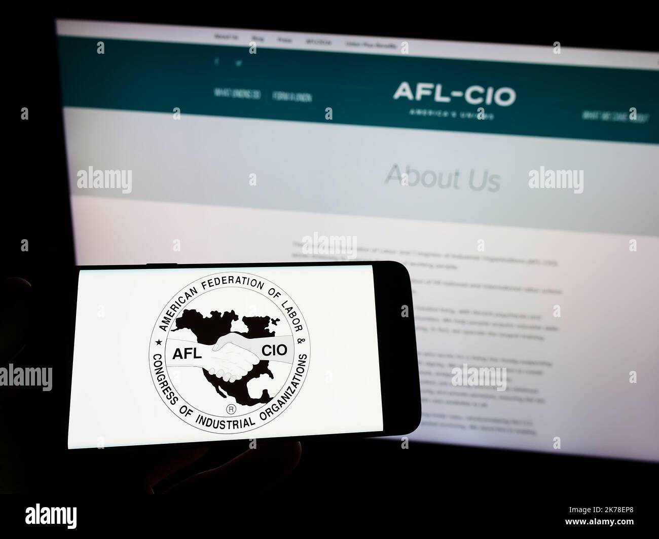 Persona che tiene in mano uno smartphone con il logo della federazione sindacale statunitense AFL-CIO sullo schermo davanti al sito Web. Messa a fuoco sul display del telefono. Foto Stock