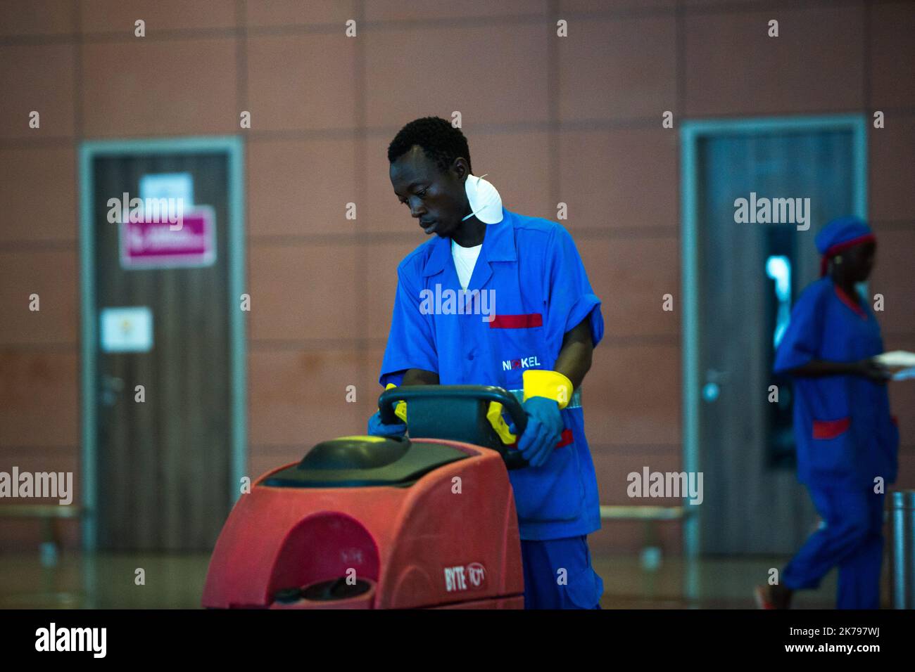Un uomo del servizio di pulizia disinfetta i corridoi dell'aeroporto di Dakar Foto Stock