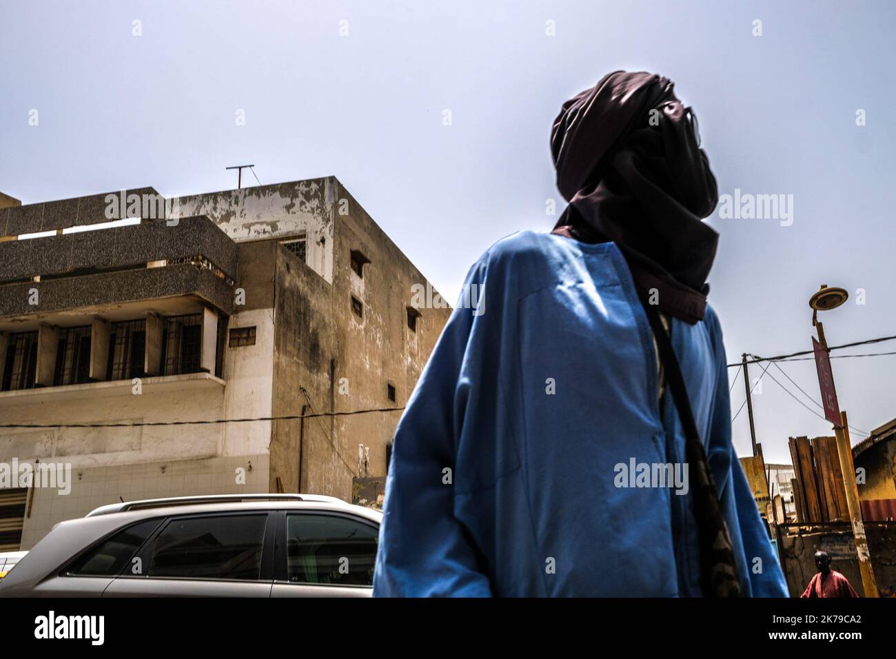 Senegal / Dakar / Dakar - un passerby protegge il suo volto con una sciarpa nel centro di Dakar. Foto Stock