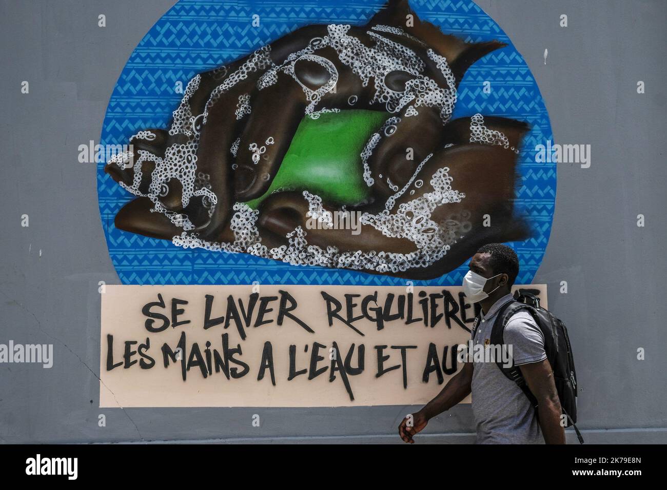 Senegal / Dakar / Dakar - Un uomo passa accanto graffiti dipinti presso l'Università di Dakar per aumentare la consapevolezza delle misure igieniche per combattere il Covid-19. Foto Stock