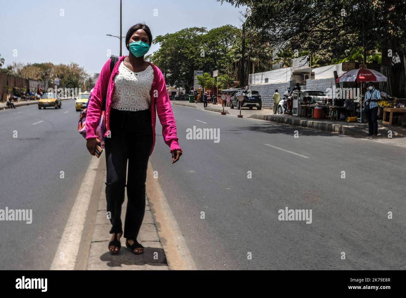 Senegal / Dakar / Dakar - Una giovane donna attende il suo taxi con la sua maschera protettiva. Foto Stock