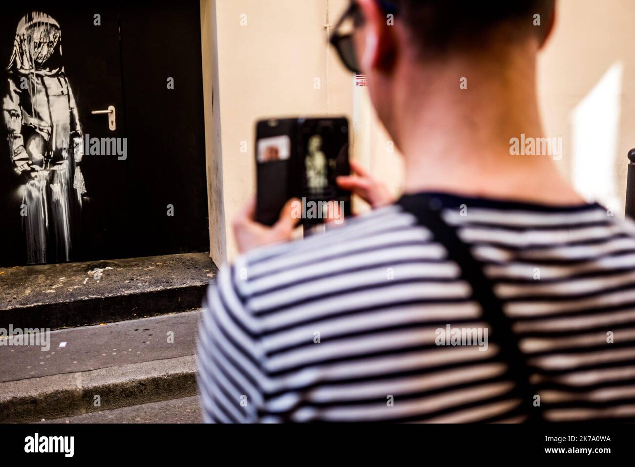 Una delle opere di Banksy. L'artista ha appena fatto la sua prima visita a Parigi. Qui, uno dei suoi stencil mostra una giovane ragazza che sembra piangere. È avvolto in una sorta di protezione. Lo stencil è stato fatto su una porta che porta al Bataclan, la sala concerti, l'obiettivo di un attacco jihadista che ha lasciato 90 morti il 13 novembre 2015. Giugno 26, 2018. Parigi. Francia. Foto Stock