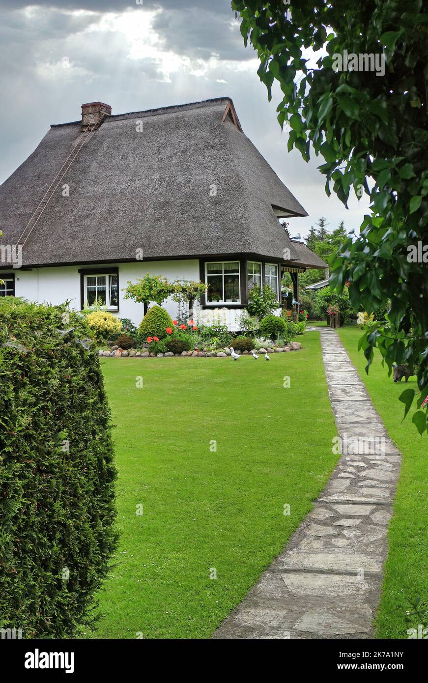Sentiero con giardino in pietra che conduce ad una casa tradizionale con tetto in paglia Foto Stock