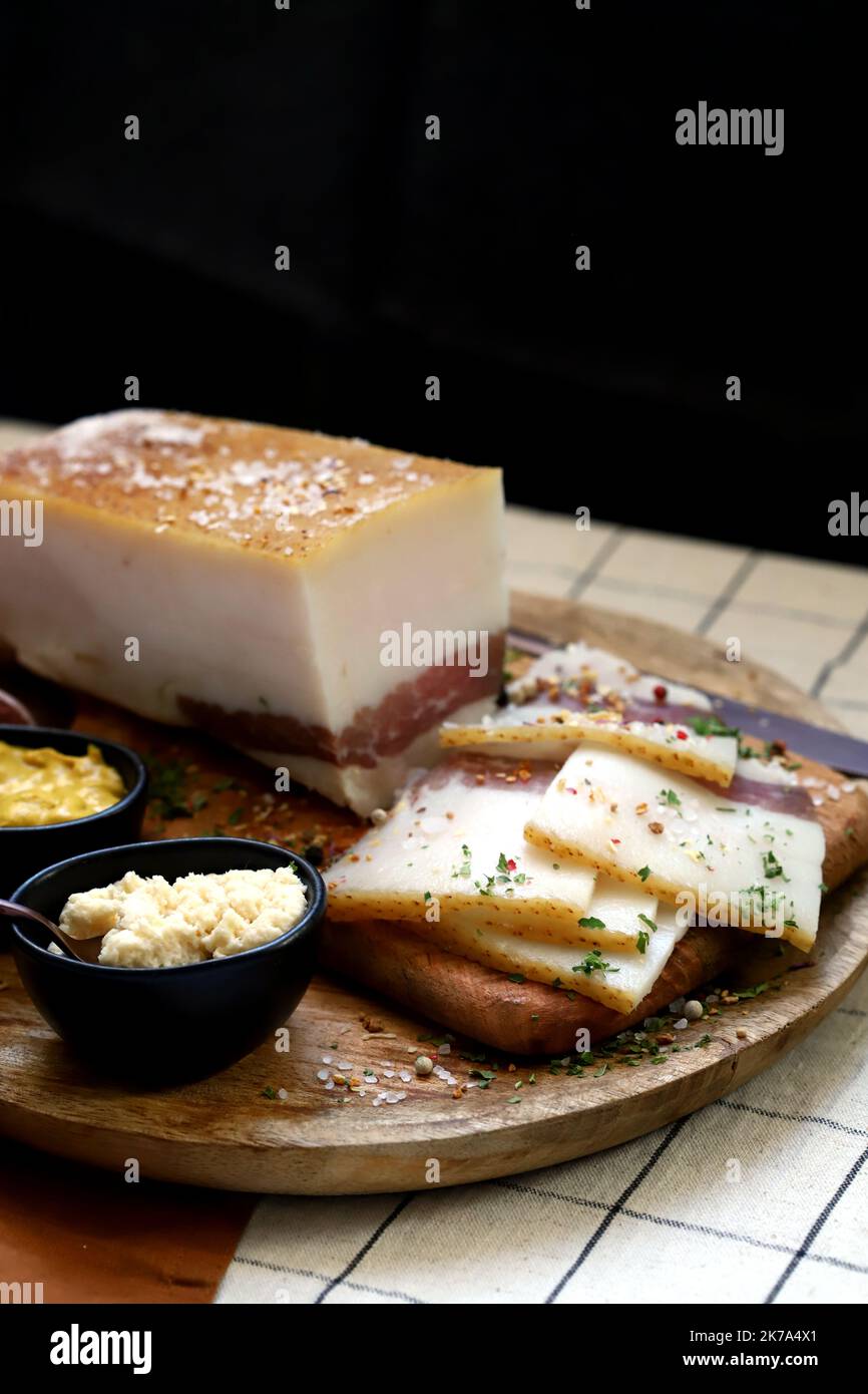 Strutto fresco con strato di carne su un asse di legno con spezie, senape e rafano. Snack delizioso. Pancetta. Foto Stock