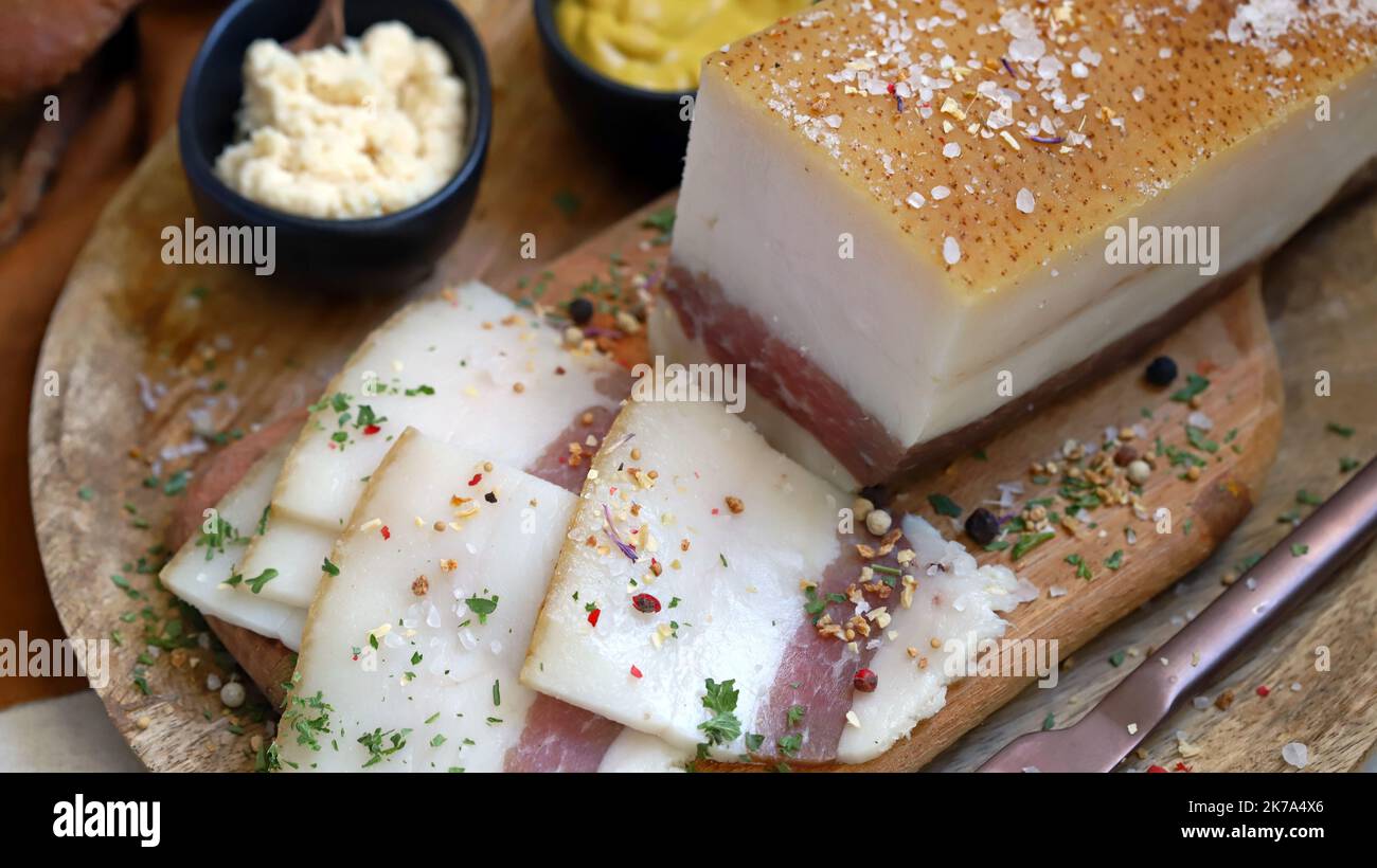 Strutto fresco con strato di carne su un asse di legno con spezie, senape e rafano. Snack delizioso. Pancetta. Foto Stock