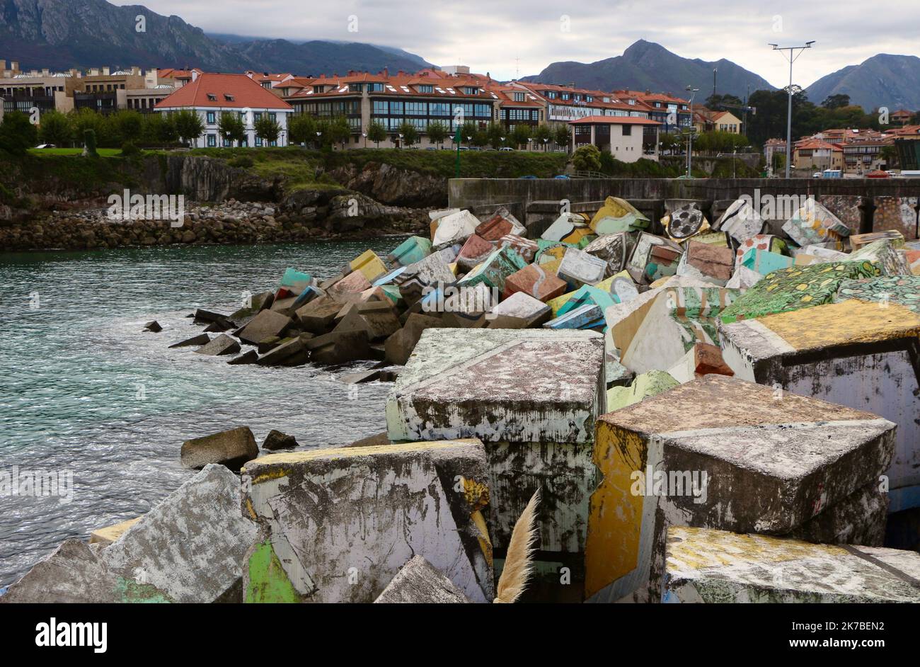 Ondate dissipando blocchi di cemento cubi di memoria dipinta da Agustin Ibarrola all'ingresso del porto Llanes Asturias Spagna Foto Stock