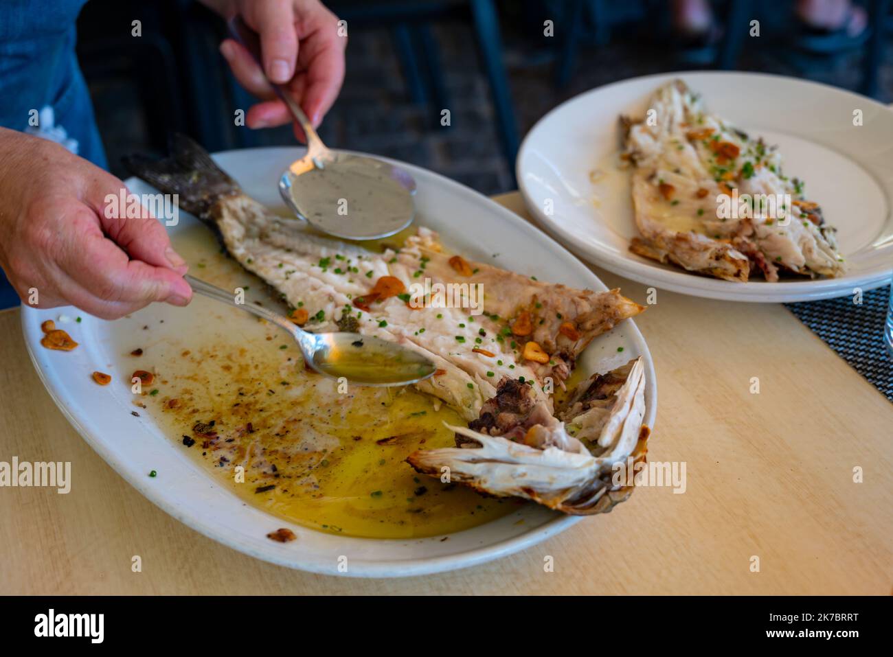 Serve in ristorante di pesce fresco alla griglia con aglio e olio d'oliva su vecchi parrillas di pesce branzino al piccolo villaggio di pescatori Getaria, basco Foto Stock