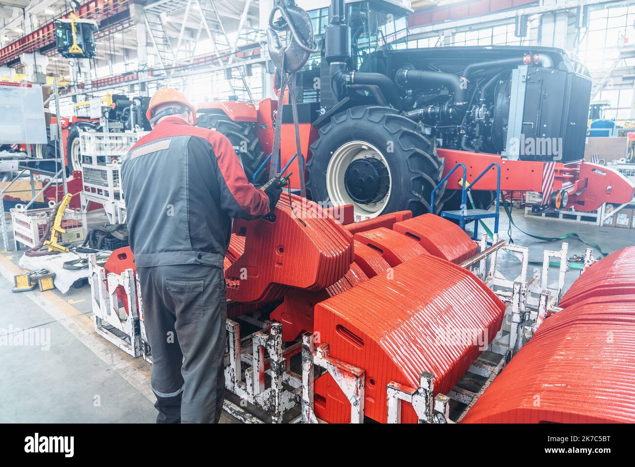 Il lavoratore industriale monta in fabbrica attrezzature agricole in una linea di produzione di trattori o mietitrebbia. Foto Stock
