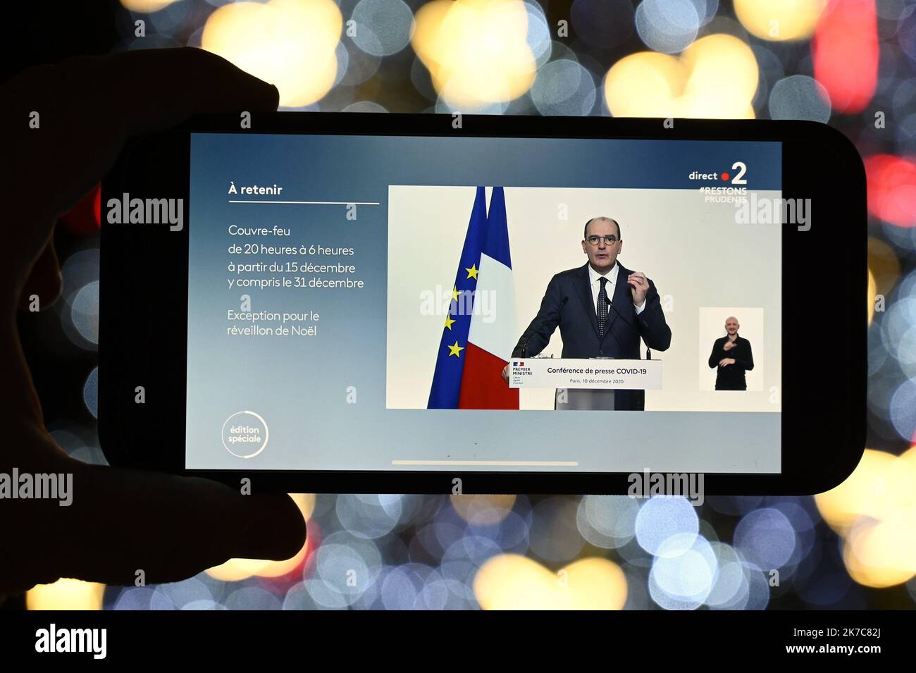 ©PHOTOPQR/L'EST REPUBLICAIN/ALEXANDRE MARCHI ; NANCY ; 10/12/2020 ; SANTE - POINT PRESSE COVID 19 - CORONAVIRUS - TELEVISIONE. Nancy 10 dicembre 2020. Sur un téléphone portable, sous les lumières du sapin de Noël de la Place Stanislas, le point presse télévisé du Premier ministre, Jean CASTEX, sur les nouvelles mesures de déconfinement et de couvre-feu à partir du 15 décmebre et pour les fêtes alors que le nombre de contaminations quotidiennes ne recule plus. FOTO Alexandre MARCHI. 2020/12/10. Su un telefono cellulare, sotto le luci dell'albero di Natale in Piazza Stanislas, la stampa televisiva Foto Stock