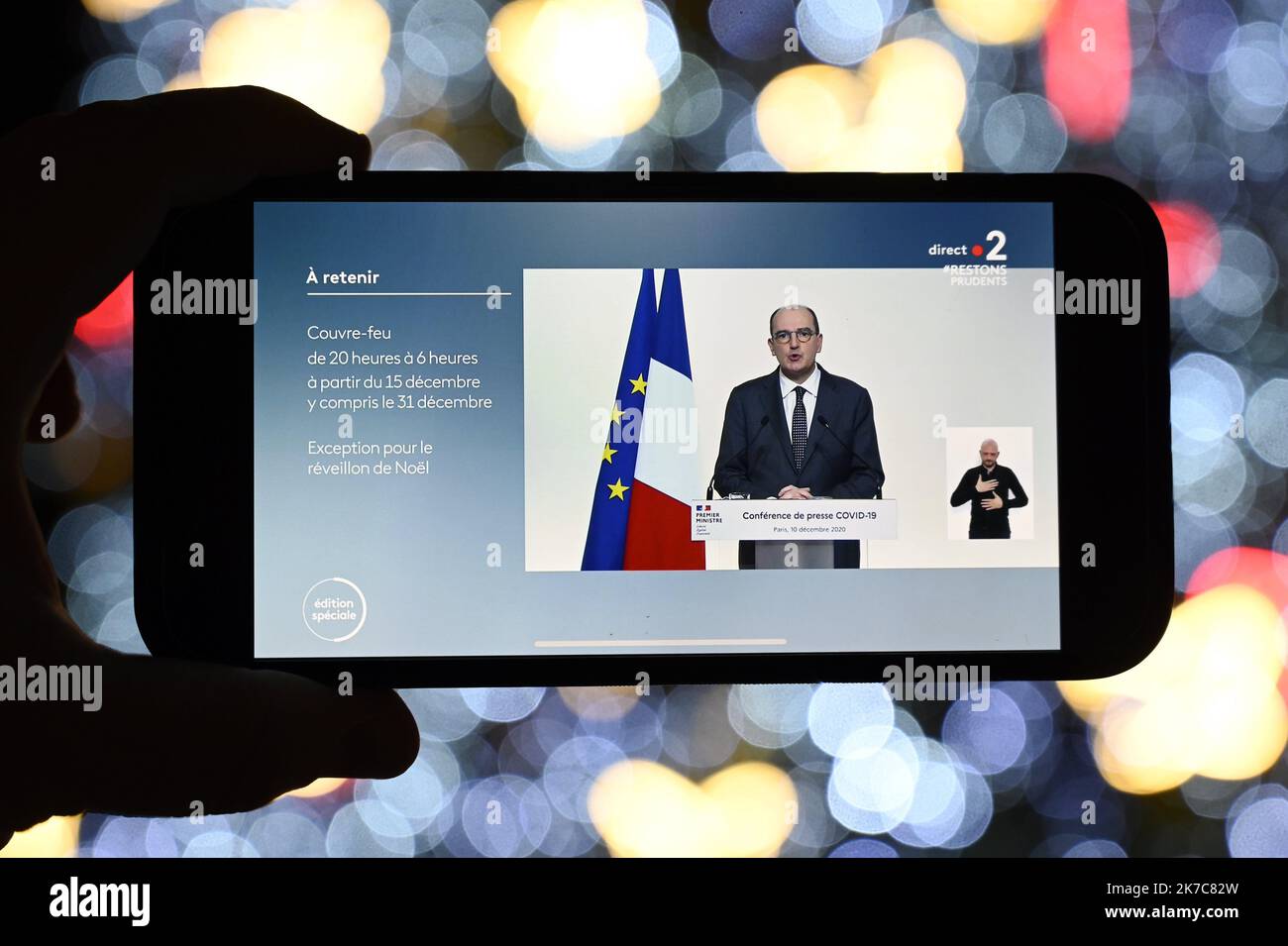 ©PHOTOPQR/L'EST REPUBLICAIN/ALEXANDRE MARCHI ; NANCY ; 10/12/2020 ; SANTE - POINT PRESSE COVID 19 - CORONAVIRUS - TELEVISIONE. Nancy 10 dicembre 2020. Sur un téléphone portable, sous les lumières du sapin de Noël de la Place Stanislas, le point presse télévisé du Premier ministre, Jean CASTEX, sur les nouvelles mesures de déconfinement et de couvre-feu à partir du 15 décmebre et pour les fêtes alors que le nombre de contaminations quotidiennes ne recule plus. FOTO Alexandre MARCHI. 2020/12/10. Su un telefono cellulare, sotto le luci dell'albero di Natale in Piazza Stanislas, la stampa televisiva Foto Stock