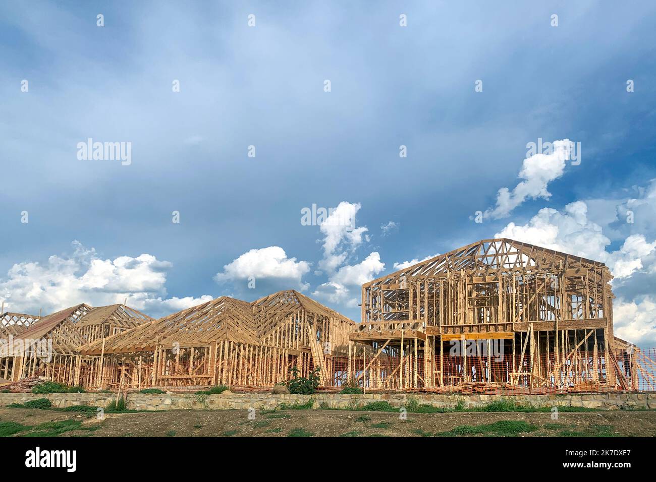 Struttura in legno residenziale cantiere con bel cielo blu sullo sfondo. Grande casa in costruzione in fase di incorniciatura. Foto Stock