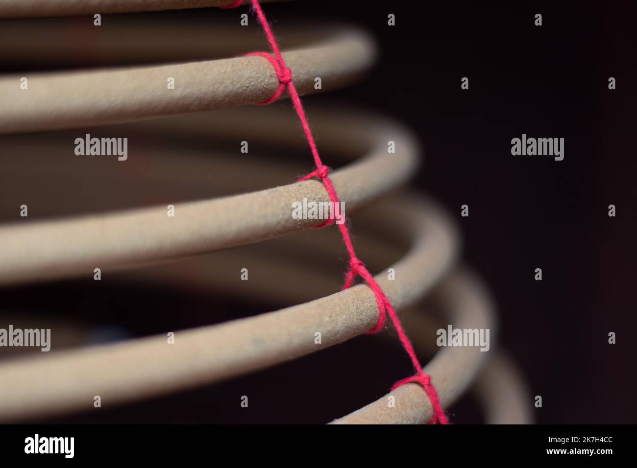 Un bruciatore di incenso a spirale è appeso su uno sfondo nero. Foto Stock