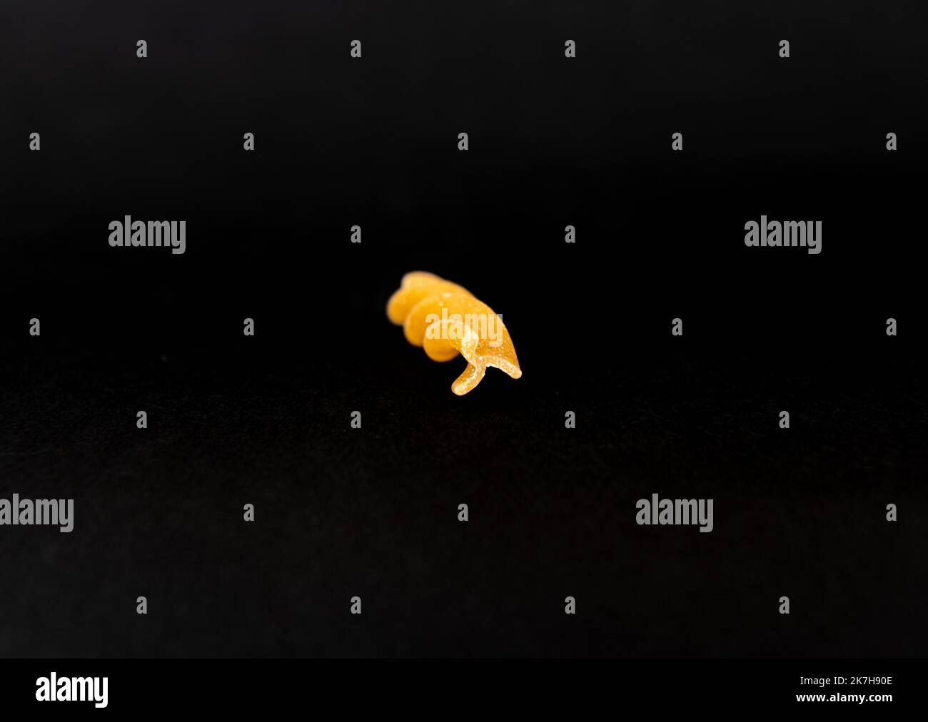 Il pezzo di pasta a spirale termina su uno sfondo nero Foto Stock