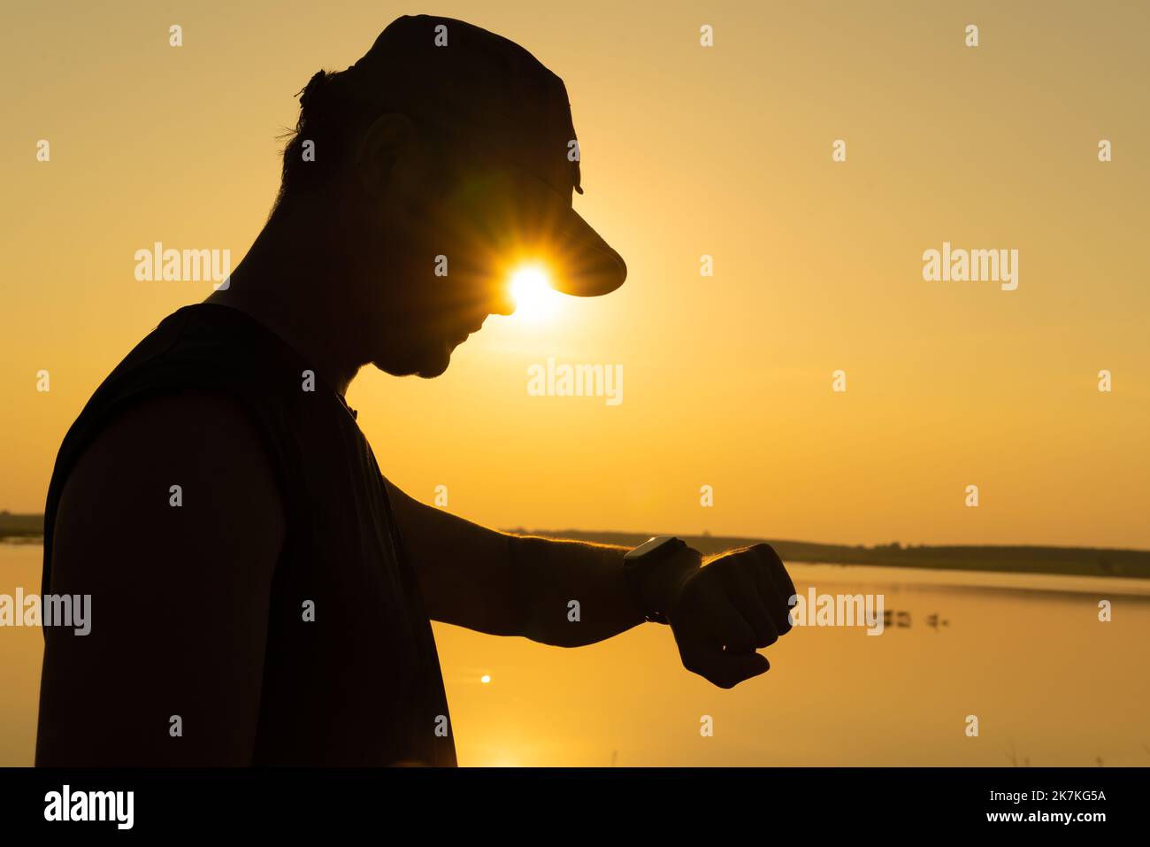 Giovane asiatico che controlla il tempo sulla vigilanza di idoneità dopo l'esercitazione vicino al tramonto. Foto Stock