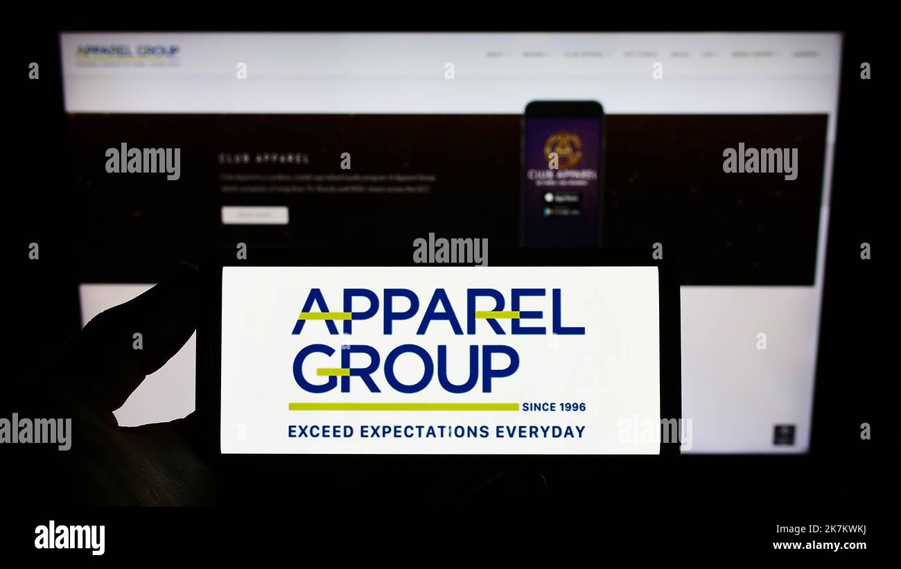 Persona che tiene in mano uno smartphone con il logo della società di vendita al dettaglio degli Emirati Apparel Group sullo schermo di fronte al sito Web. Messa a fuoco sul display del telefono. Foto Stock