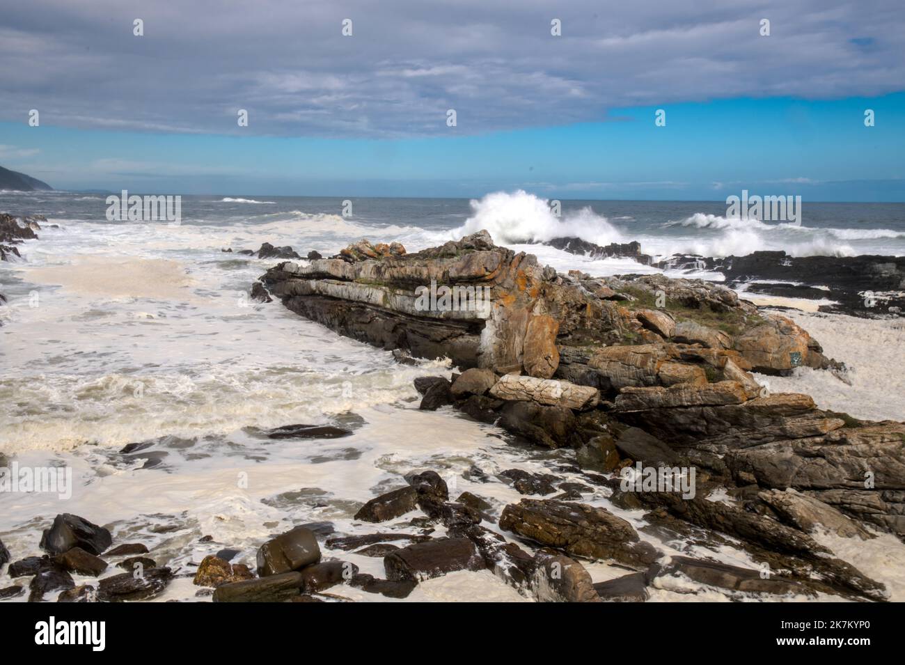 Maree dentro alle tempeste Fiume con marea dentro e massici demolitori che si schiantano sulla costa rocciosa. Bassa velocità dell'otturatore con linee di punta e navigazione schiumosa Foto Stock