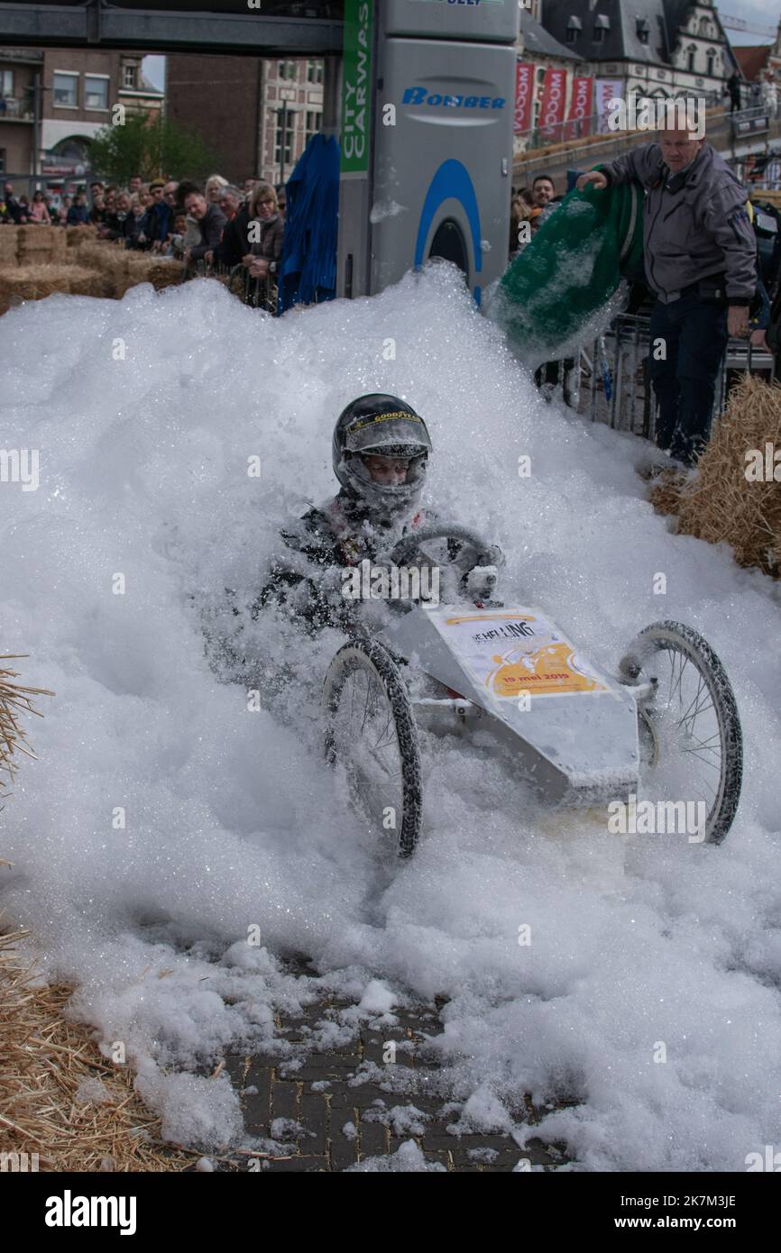 Sint Niklaas, Belgio, 05 maggio 2019, il giovane uomo guida un go-kart personalizzato a tre ruote attraverso una montagna di schiuma durante una gara di scatola di sapone Foto Stock
