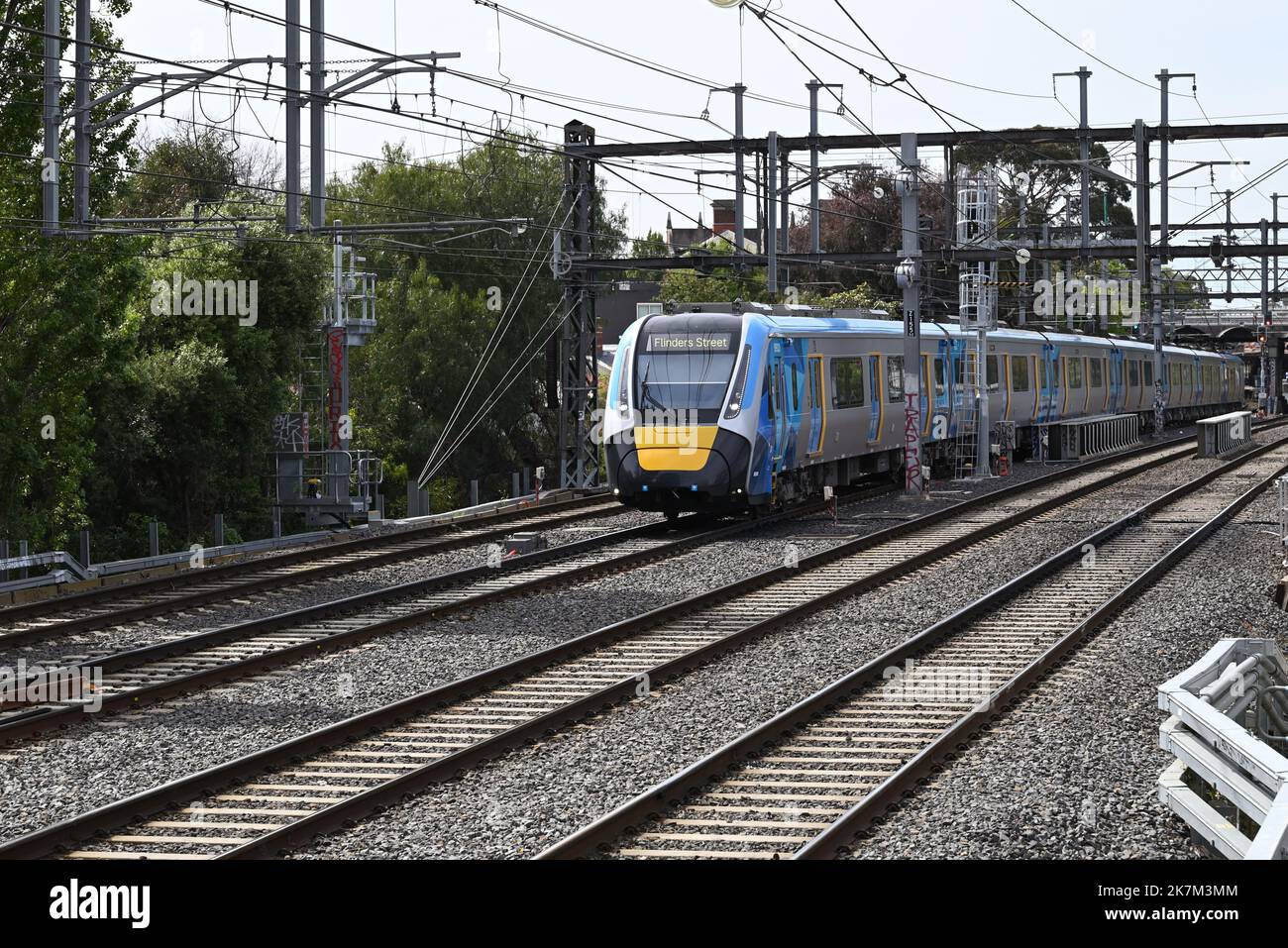 Un nuovo HCMT, con l'attuale metro giallo e blu treni la livrea di Melbourne, viaggiando attraverso i sobborghi interni verso la stazione di Flinders Street Foto Stock