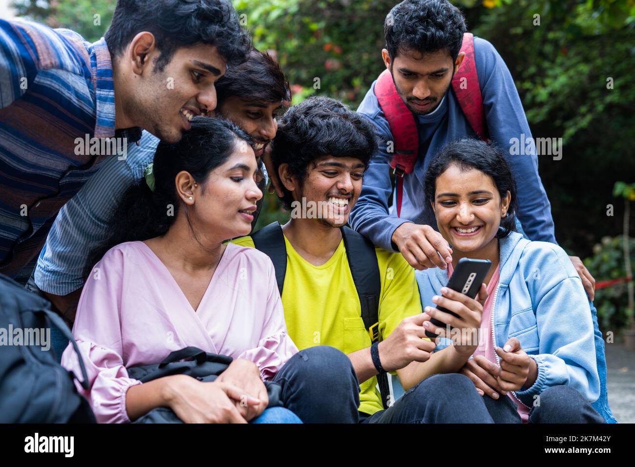 gruppo di studenti universitari che utilizzano i social media o che guardano i momenti di intrattenimento sul telefono cellulare durante il tempo libero al collage campus park - concetto di Foto Stock