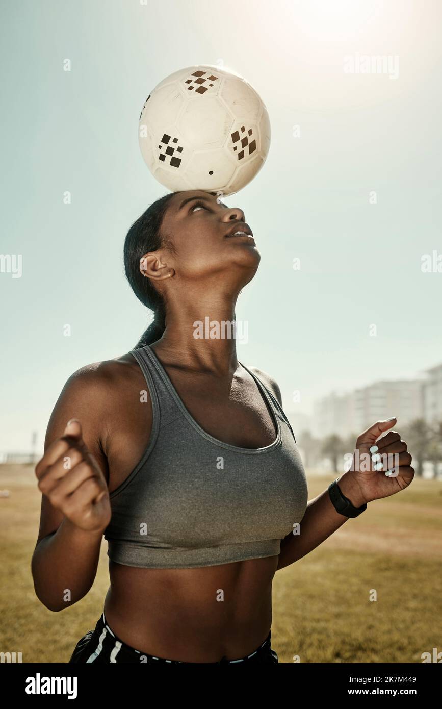 Donna, palla da calcio e equilibrio sulla testa in campo di allenamento erba, campo sportivo o fitness club. Giocatore di calcio, donna nera e atleta Foto Stock