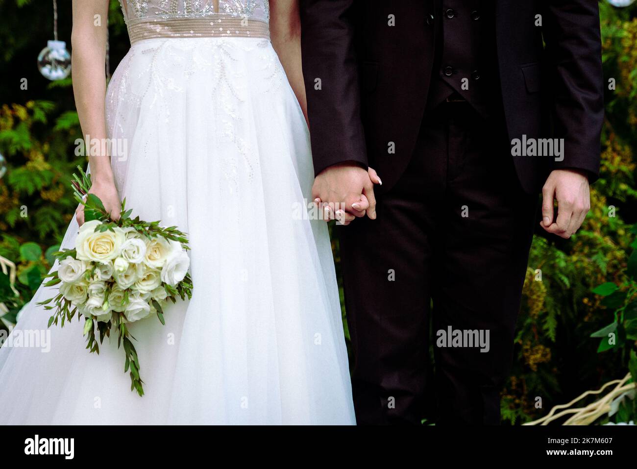 La sposa tiene un bouquet di nozze dalle rose nelle sue mani, fiori di giorno di nozze. Bel bouquet di fiori bohémien matrimonio. Ragazza in un abito con un bouq Foto Stock