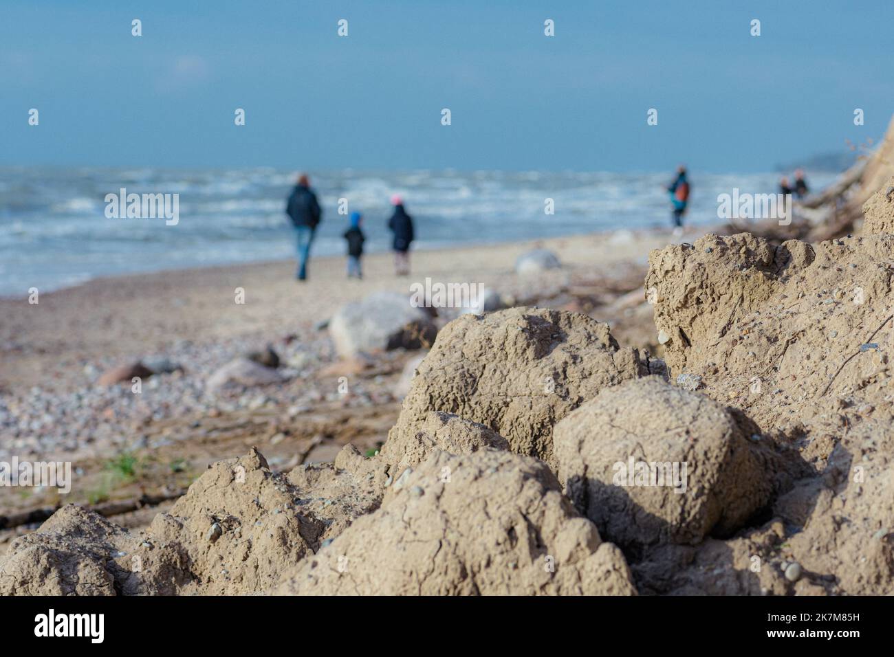 Rocce, pietre e sabbia cadono da una scogliera sulla spiaggia con persone che camminano sulla riva. Concetto di erosione. Mar Baltico, Lituania Foto Stock