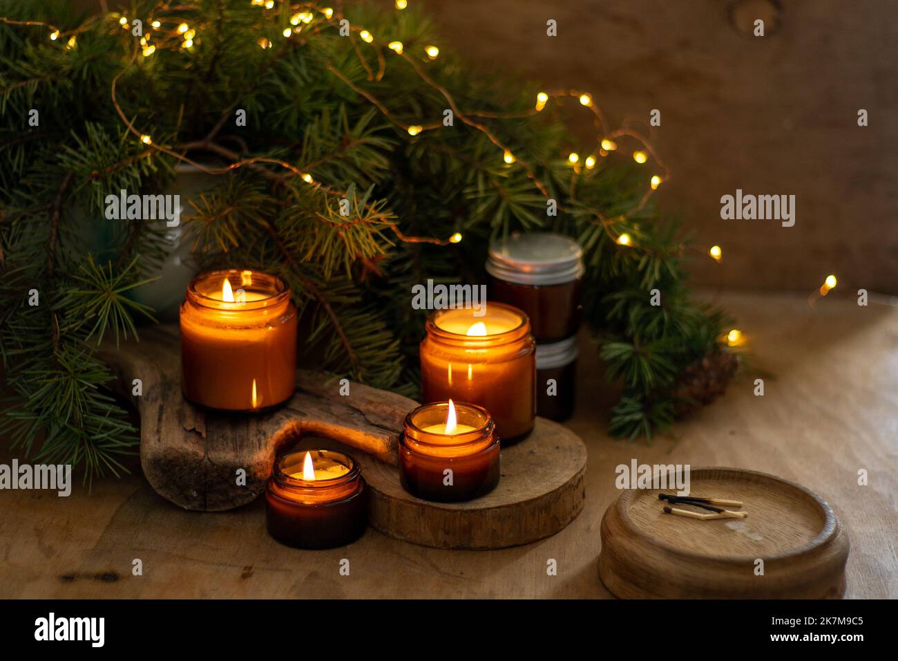 Le candele di soia bruciano in vasi di vetro. Comfort a casa. Candela in un vaso marrone. Profumo e luce. Candela profumata fatta a mano. Aromaterapia. Albero di Natale e umore invernale. Arredamento accogliente. Decorazione festiva. Foto Stock