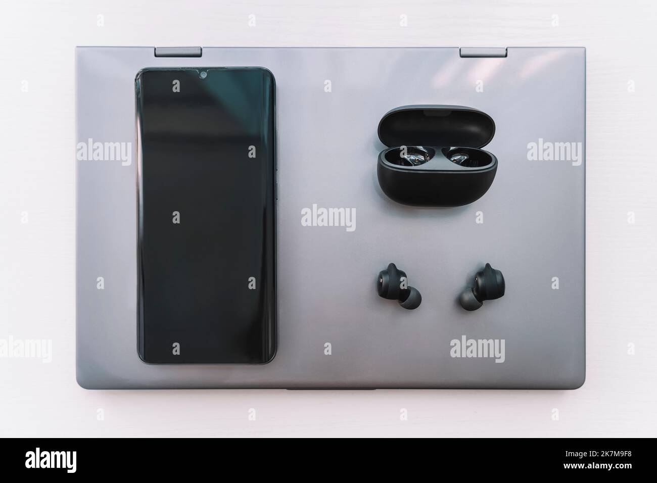 Un computer portatile, cuffie e uno smartphone su un desktop di legno. Foto Stock