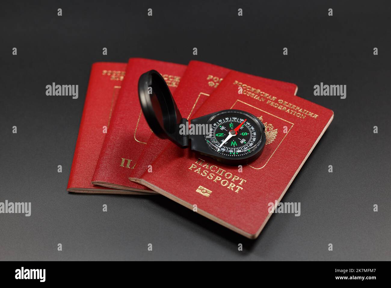 Quattro passaporti stranieri russi su uno sfondo scuro e una bussola che si trova su di essi puntando a sud-est. Concetto di viaggio nel sud-est asiatico Foto Stock