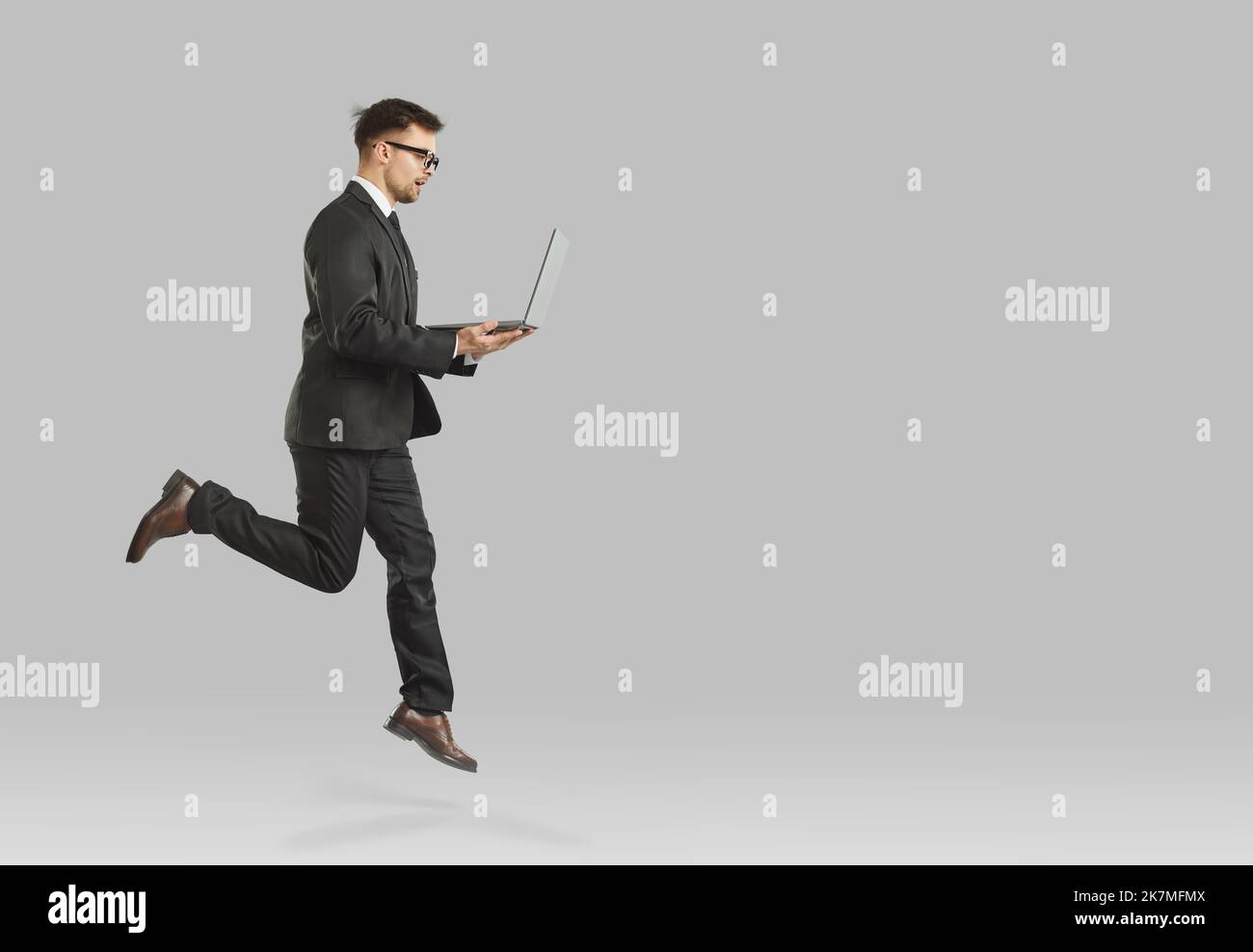 Dirigente o finanziere professionista maschile che salta con un notebook che simboleggia la crescita della carriera. Foto Stock
