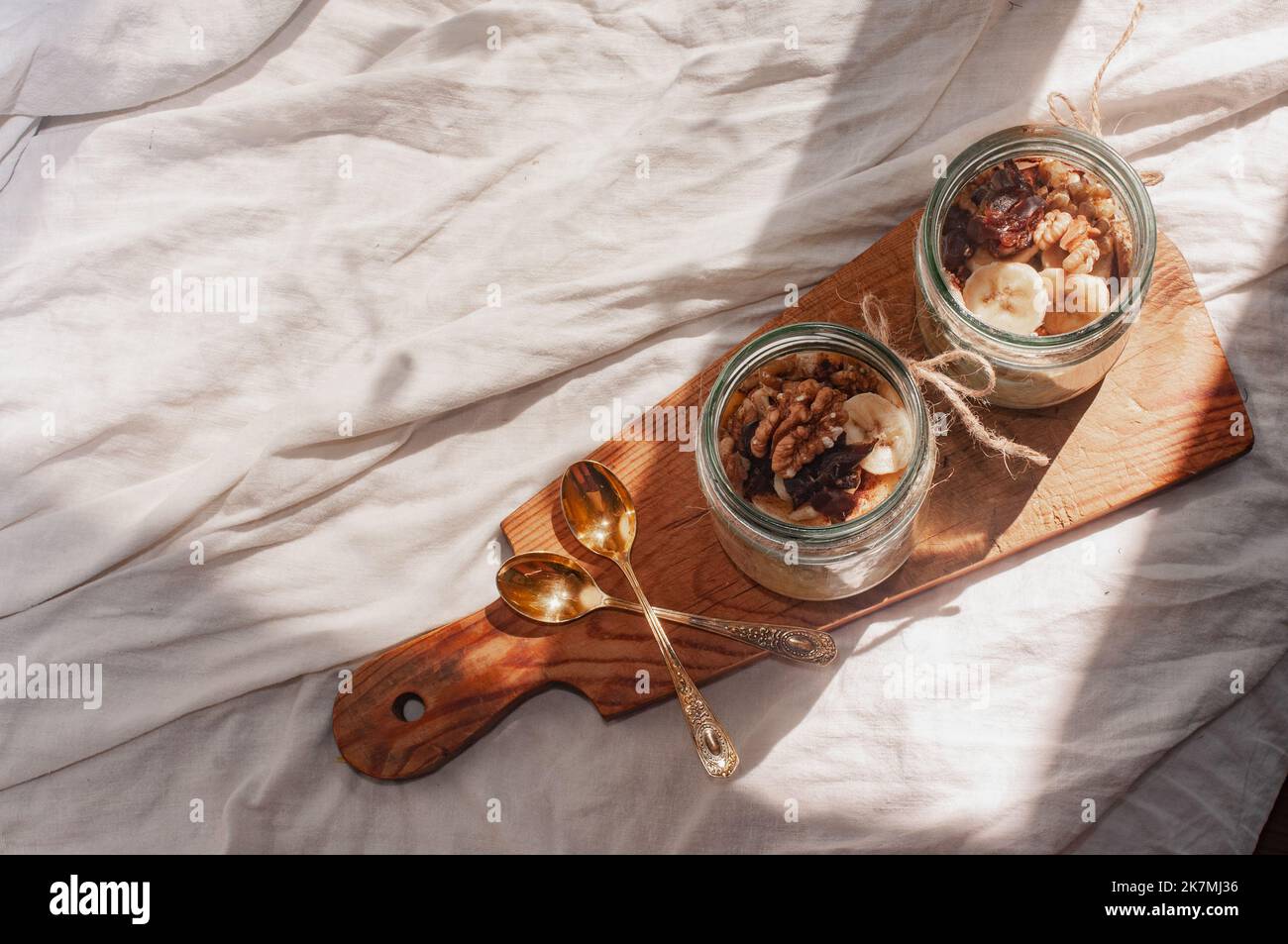 Delizioso durante la notte non cuoco vegan crudo farina d'avena rustica in un vaso con banana e datteri su sfondo minimalistic bello e neutro beige Foto Stock