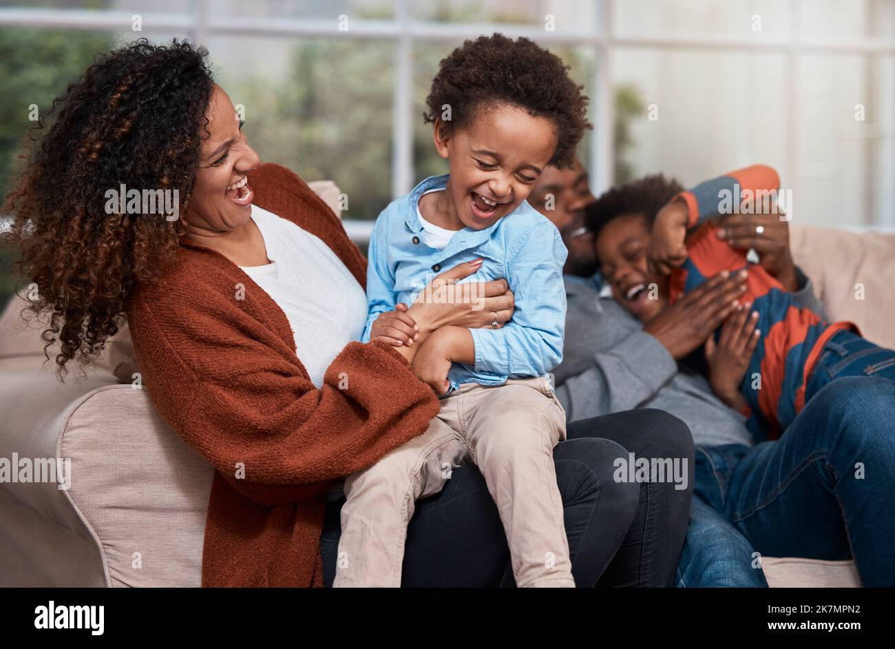 È sempre divertente essere in giro con la famiglia. una famiglia felice che si diverte insieme su un divano a casa. Foto Stock
