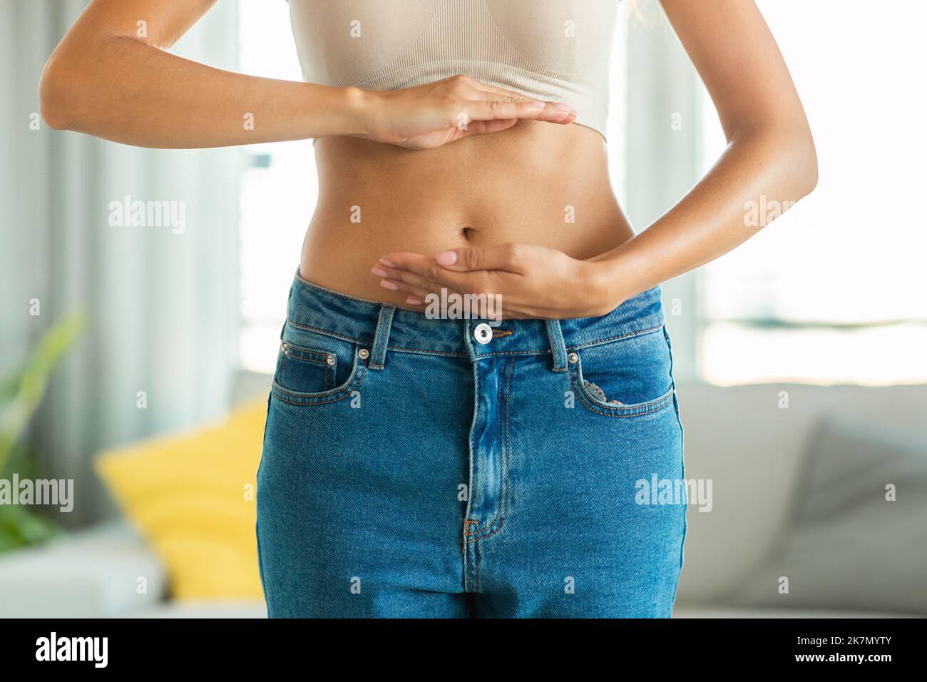 Unriconoscibile Slim Woman Framing Flat stomaco e Belly Button Indoor Foto Stock