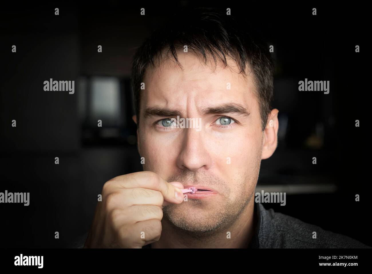 tenere la bocca chiusa concetto. L'uomo triste chiude la bocca. Silenzio. Giovane ragazzo carino cerca di aprire la bocca chiusa. Foto Stock