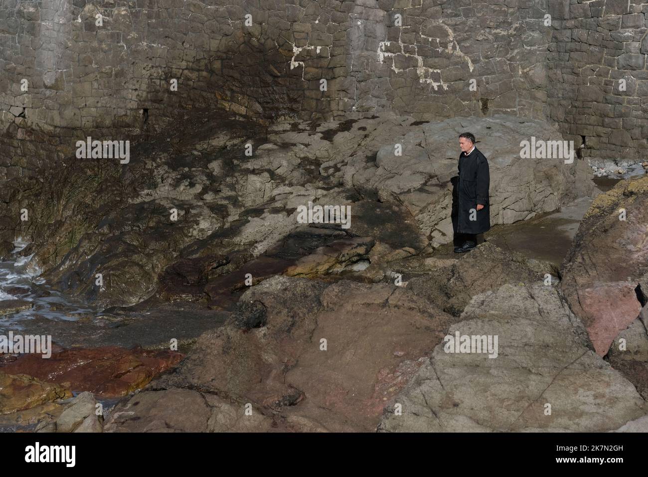 Un uomo solitario in piedi su alcune rocce Foto Stock