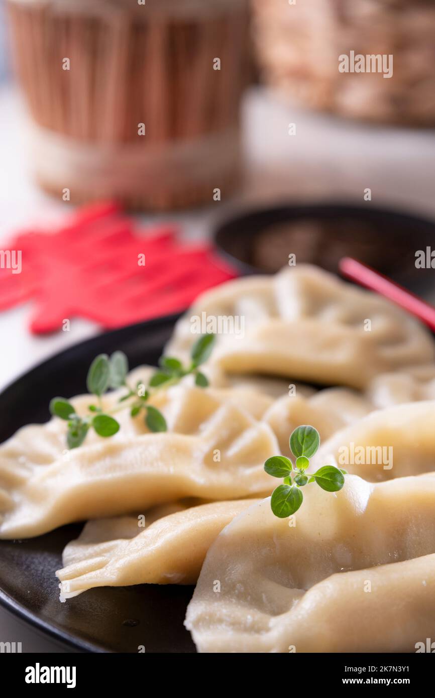 Somma dim. Gnocchi cinesi fatti in casa sono serviti su un piatto nero. Mangiano con le bacchette. Cucina orientale, spuntini leggeri per un pranzo tradizionale. . Foto di alta qualità. Foto Stock