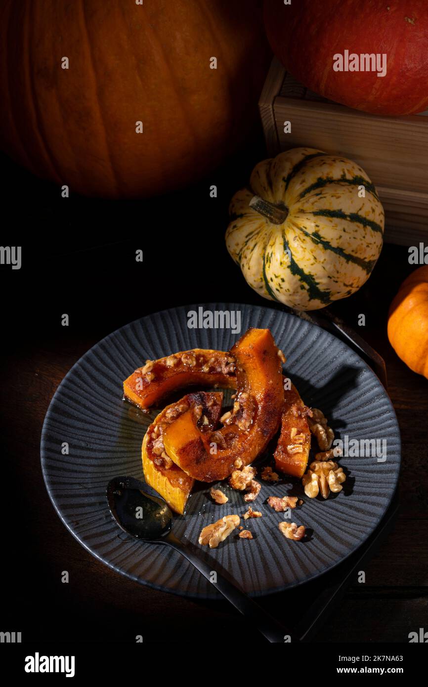 Scuro moody pittorico fermo-vita di autunno arrosto zucca zucca zucca zucca zucca zucca spolverata con cannella, noci e miele Foto Stock