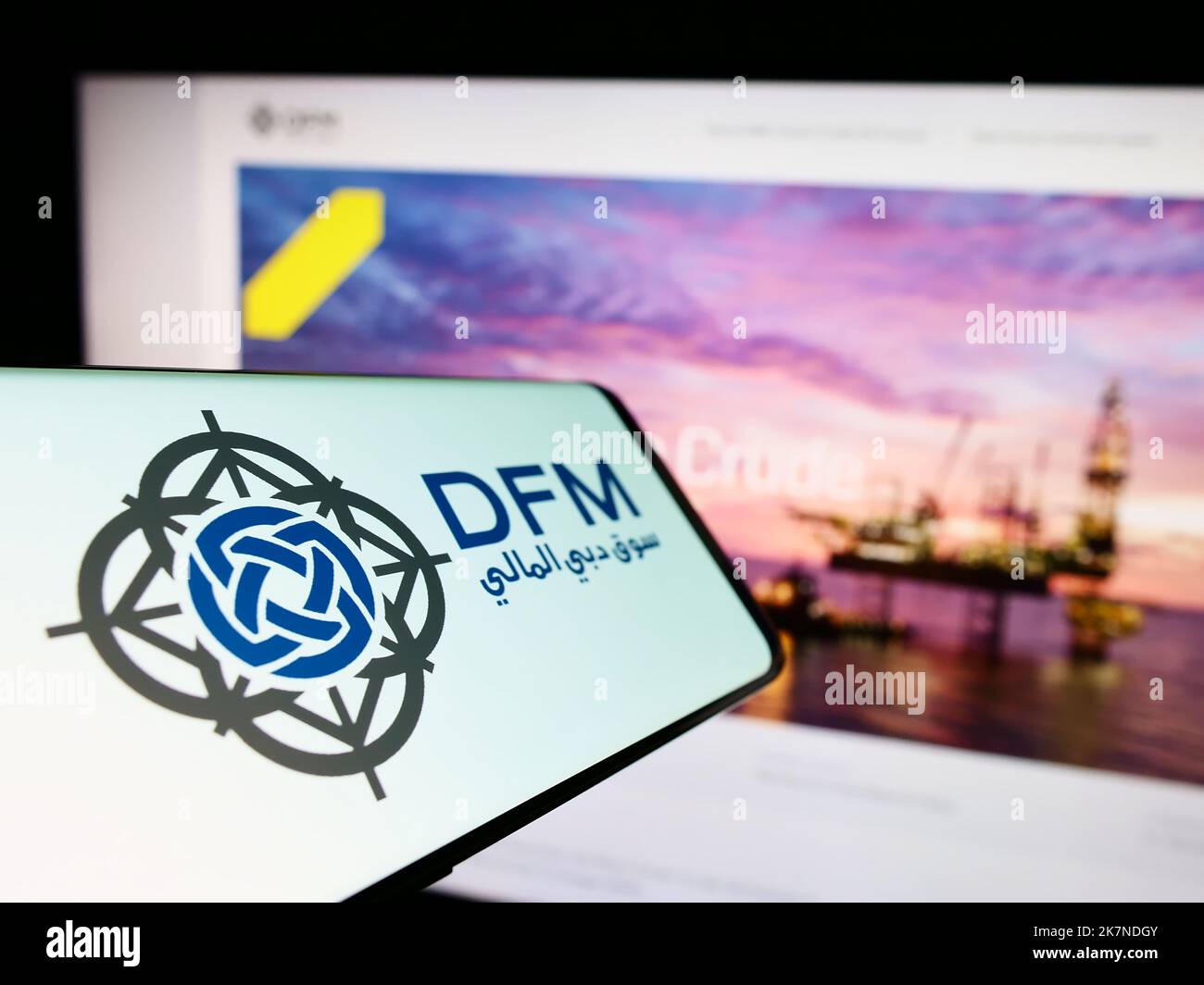 Telefono cellulare con logo della borsa Dubai Financial Market (DFM) sullo schermo di fronte al sito web della società. Messa a fuoco al centro del display del telefono. Foto Stock